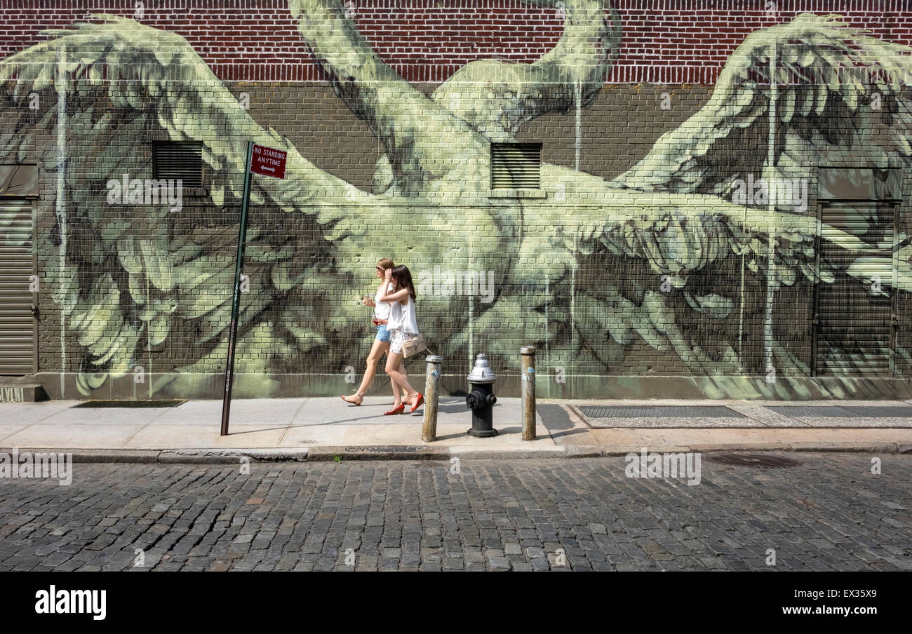 Zwei junge Frauen in kurzen Hosen vorbei ein street-Art-Wandbild der Paarung Schwäne in New York City NYC Stockfoto