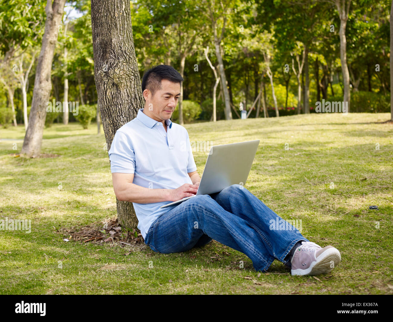 asiatischer Mann mit Laptop im freien Stockfoto