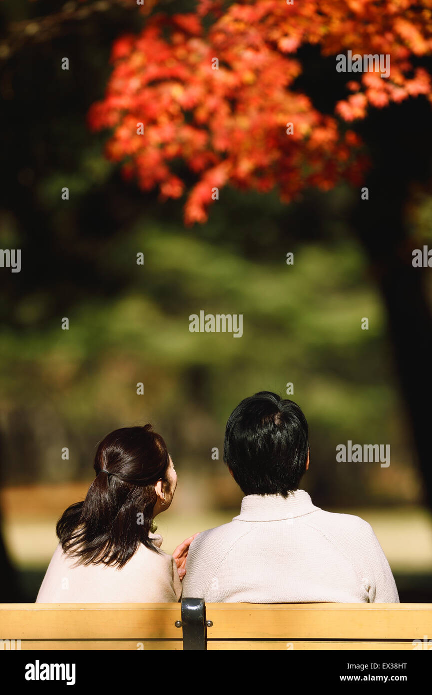 Senior japanische paar sitzt auf einer Bank im Stadtpark Stockfoto