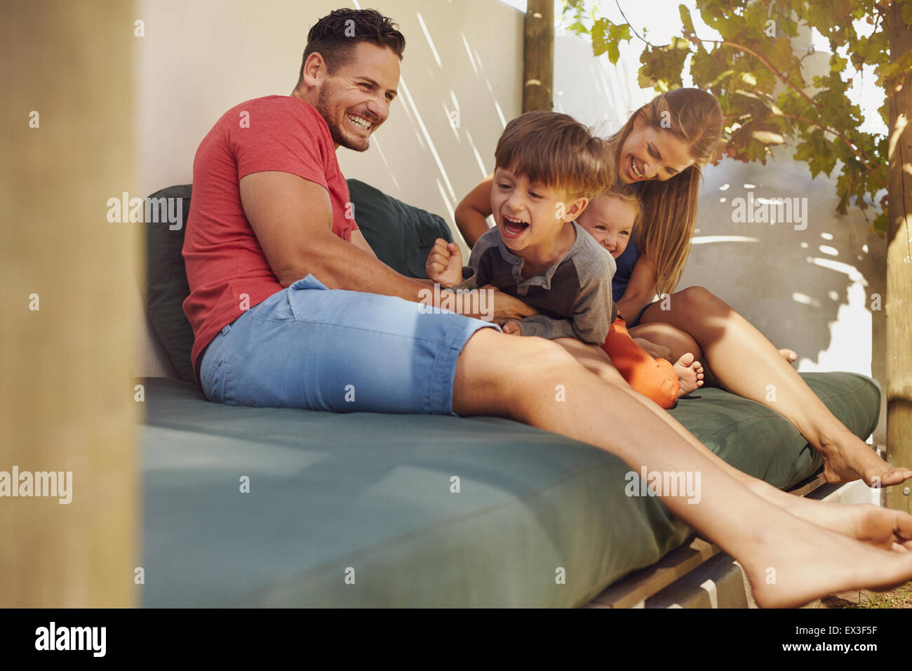 Glückliche Familie Zusammensitzen im Hinterhof, Spaß zu haben. Vater und Mutter mit ihren Kindern spielen, beim Sitzen im Innenhof. Stockfoto