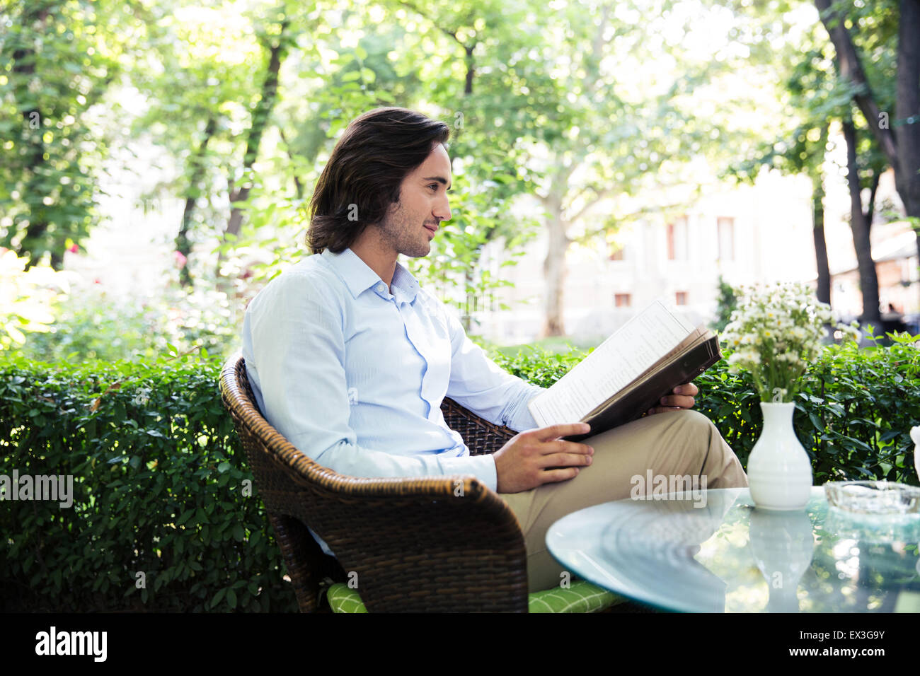 Junger Mann hält Menü im Café im freien Stockfoto