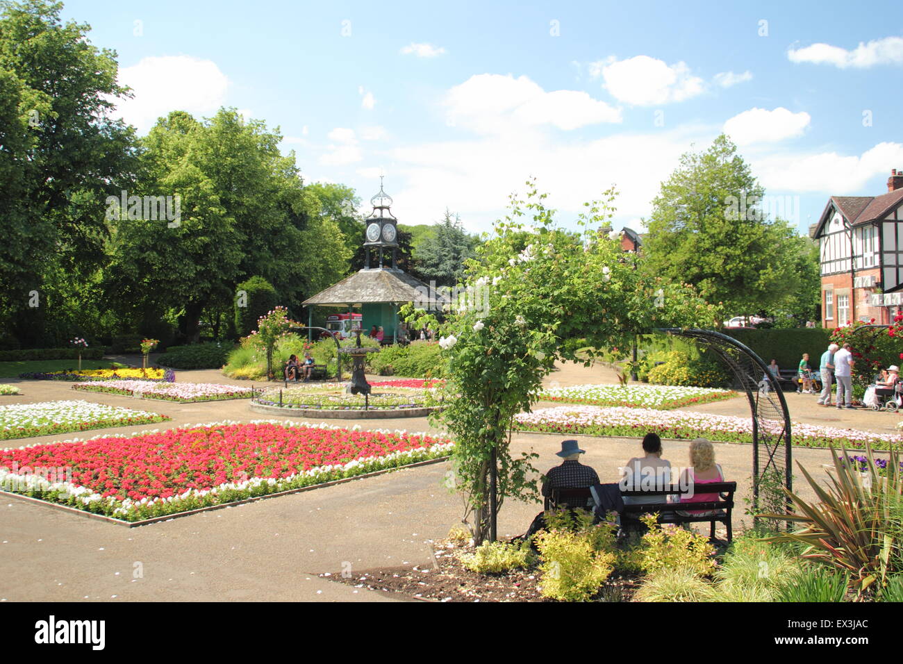 Menschen sitzen auf einer Bank unter einem rose Bogen an einem heißen Sommertag in Hall Leys Park, Matlock, Derbyshire Dales England UK Stockfoto