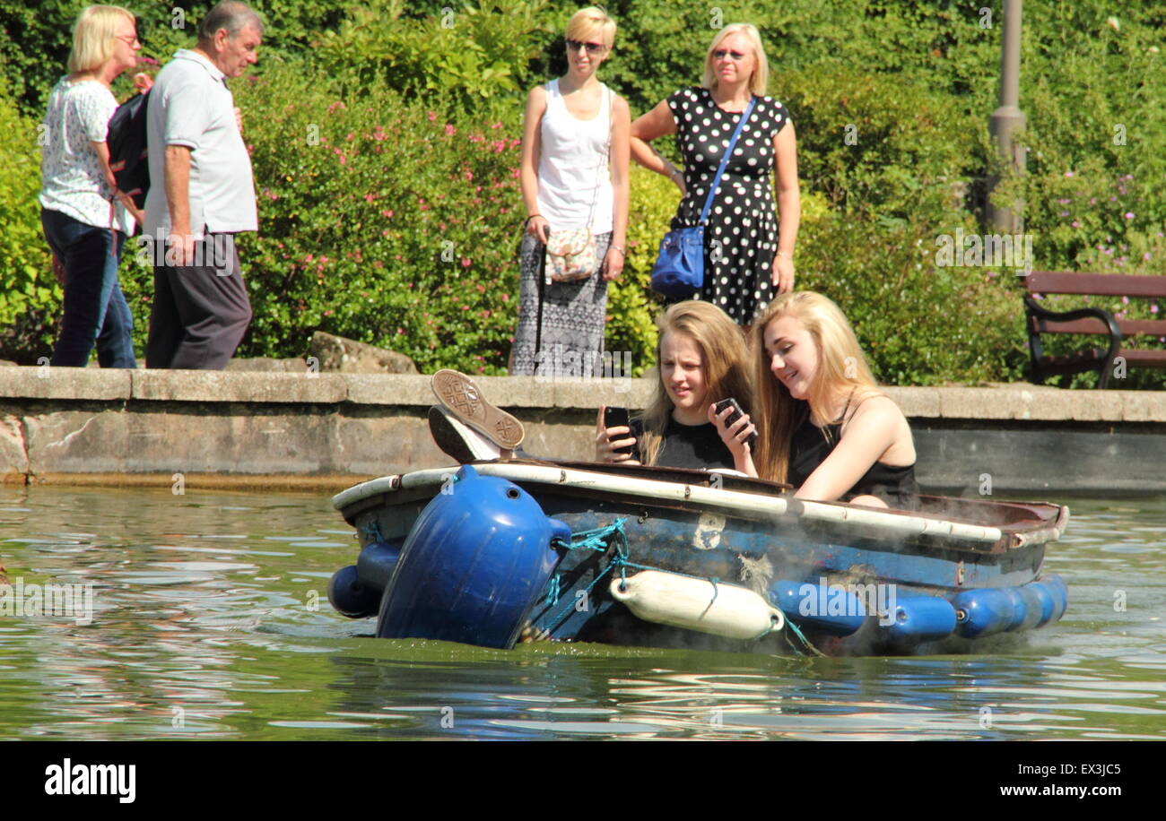 Mädchen im Teenageralter betrachten ihre Handys während der Fahrt auf einen See mit Booten, Matlock, Derbyshire England UK Stockfoto
