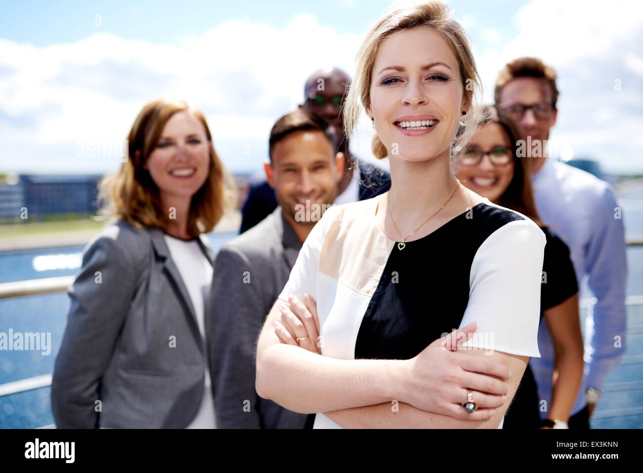 Weiße weibliche executive stand vor Kollegen mit Armen gekreuzt Lächeln auf den Lippen. Stockfoto