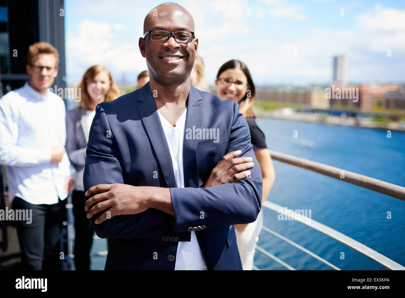 Schwarzen männlichen executive stehend mit Arme gekreuzt vor Kollegen Stockfoto
