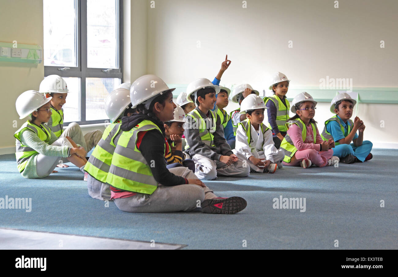 Junge Schulkinder ware Schutzhelme und hohe Vis Jacken auf einer Website zu besuchen, um eine neue Erweiterung zu ihrer Schule Stockfoto