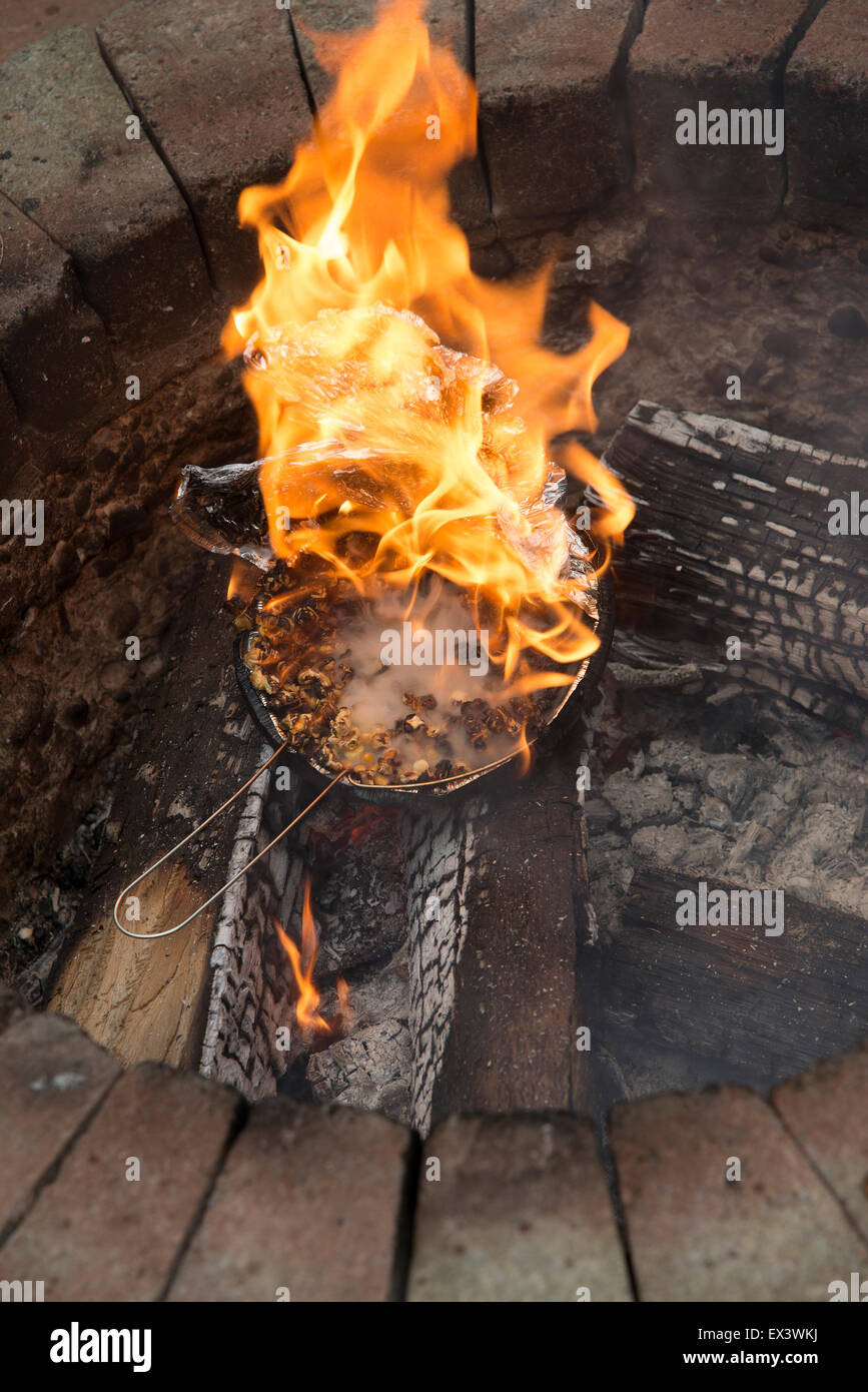 Popcorn in einer Folie abgedeckten Pfanne explodiert und in einem Garten Feuerstelle Flammen mit Popcorn nun ungenießbar brennenden Feuer fängt Stockfoto