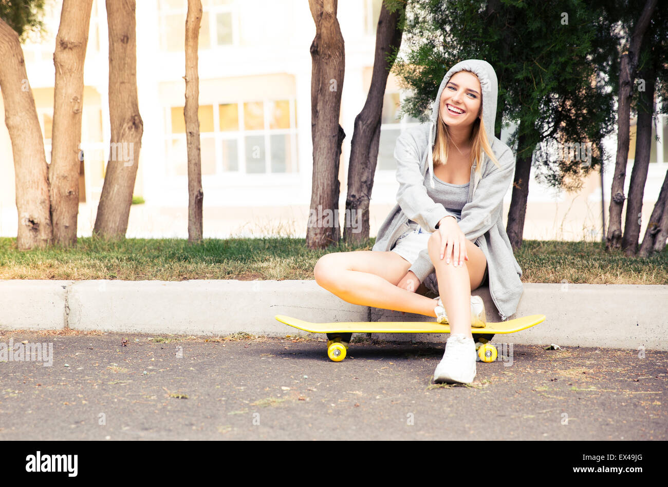 Fröhliches junges Mädchen ruhen mit Skateboard im freien Stockfoto