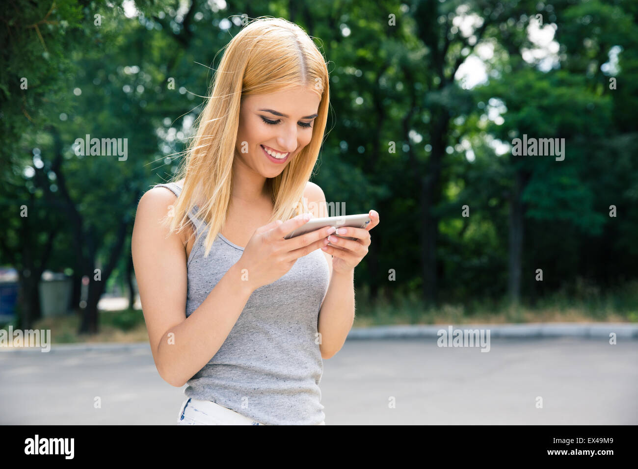 Fröhliches junges Mädchen mit Smartphone im freien Stockfoto
