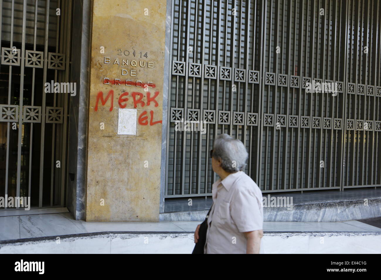 Athen, Griechenland. 6. Juli 2015. Eine Frau geht durch ein Zeichen außerhalb der Bank von Griechenland, der "Bank de Merkel" geändert wurde. Bildnachweis: Michael Debets/Alamy Live-Nachrichten Stockfoto