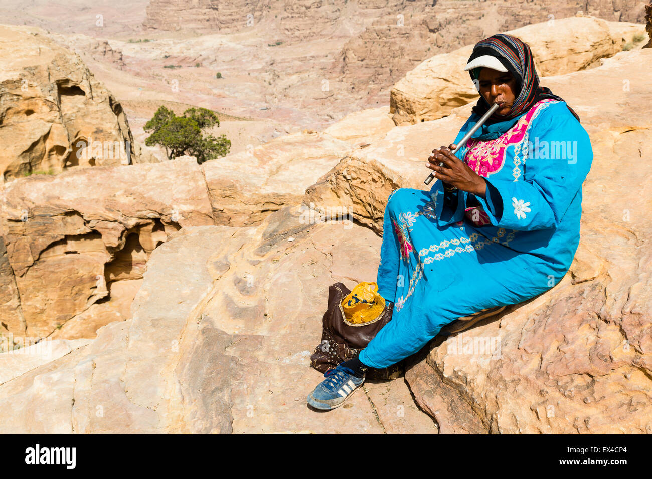 Petra, Jordanien, 8. Juni. Beduinen-Frau eine kleine Metall Flötenspiel auf einem Felsvorsprung in Petra. Stockfoto