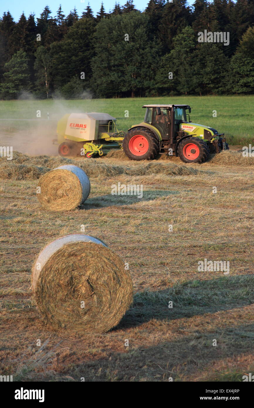 Landwirt Traktor sammeln und pressen Heu in Rundballen. Bayern
