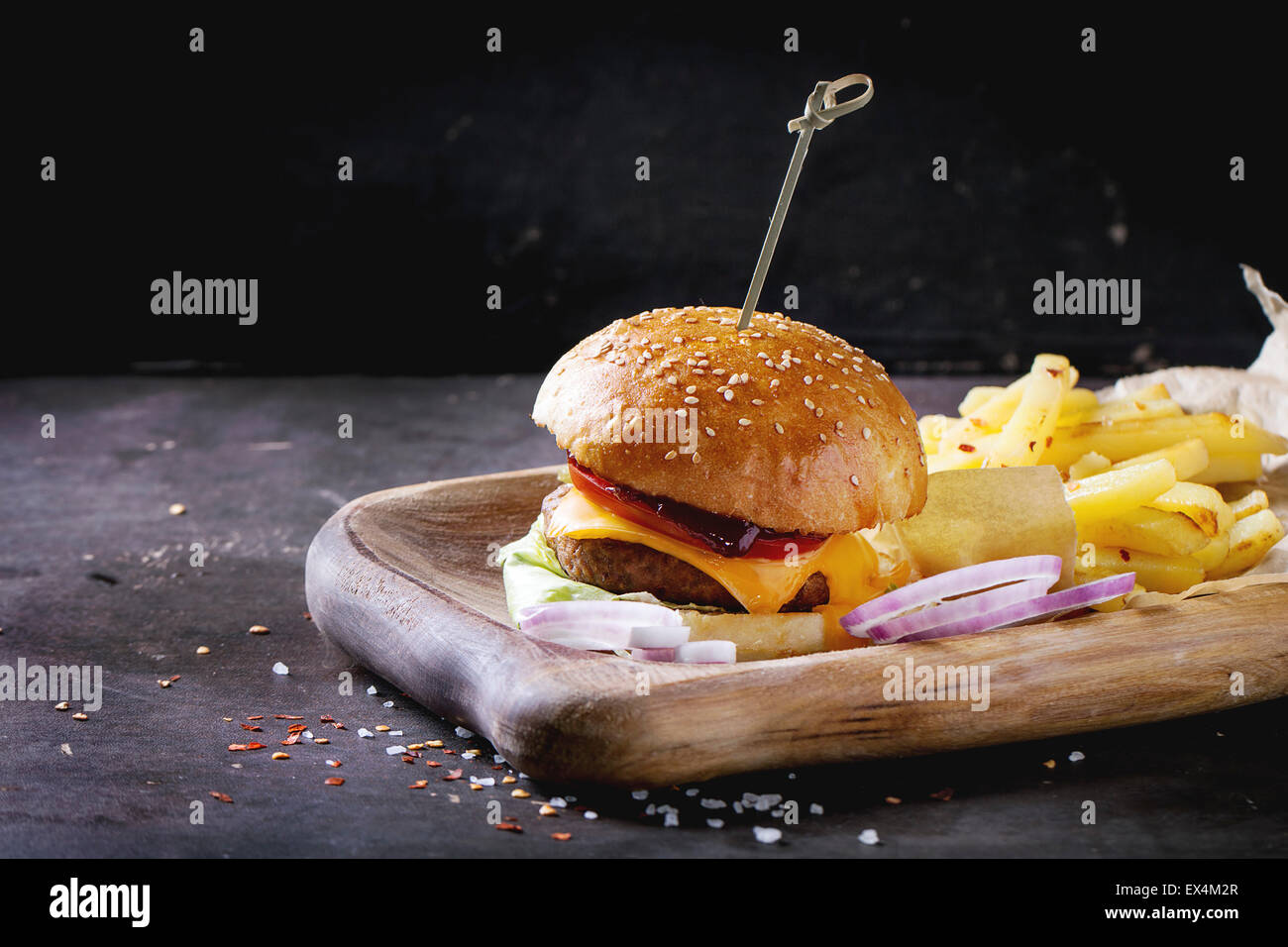 Holzplatte mit frischen hausgemachten Burger und gegrillte Kartoffeln auf dunklem Hintergrund. Stockfoto