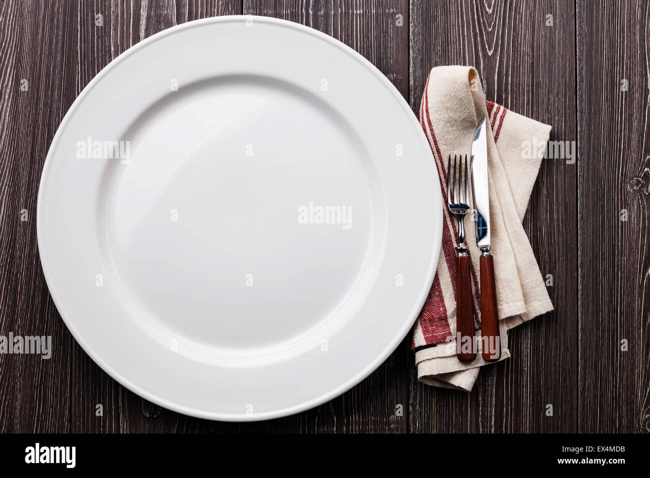 Weißen leeren Teller mit Gabel und Messer auf grauem Hintergrund aus Holz Stockfoto