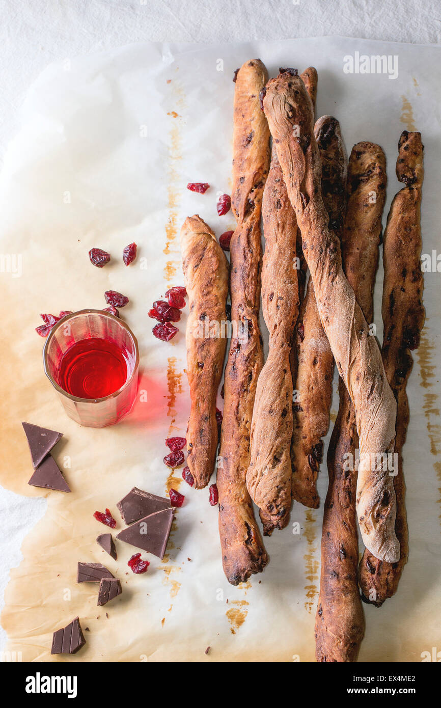 Frisch gebackene hausgemachte süße Schokolade Grissini Brot Sticks über Backpapier mit Glas roten Beeren Likör auf weiße Tischdecke Stockfoto