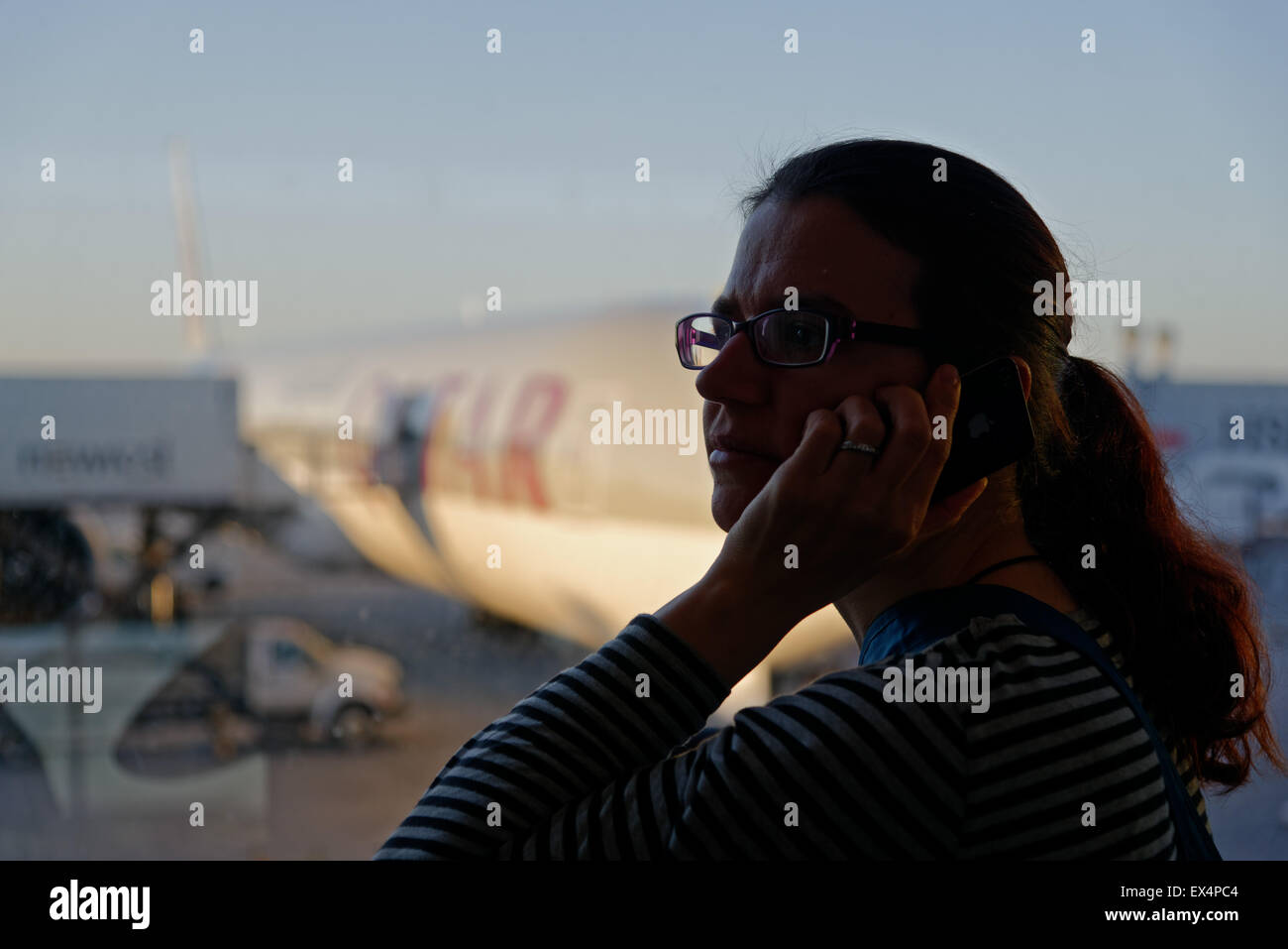Eine Frau mit einem Handy an einem Flughafen Stockfoto