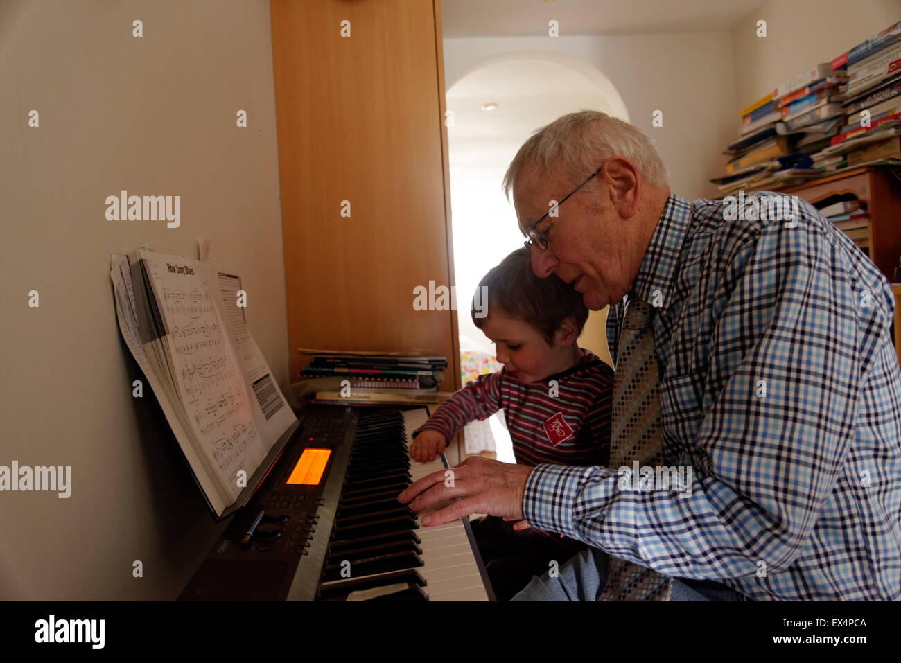 Ein Junge (3 Jahre alt) Spielen auf der Klavier mit seinem Großvater Stockfoto