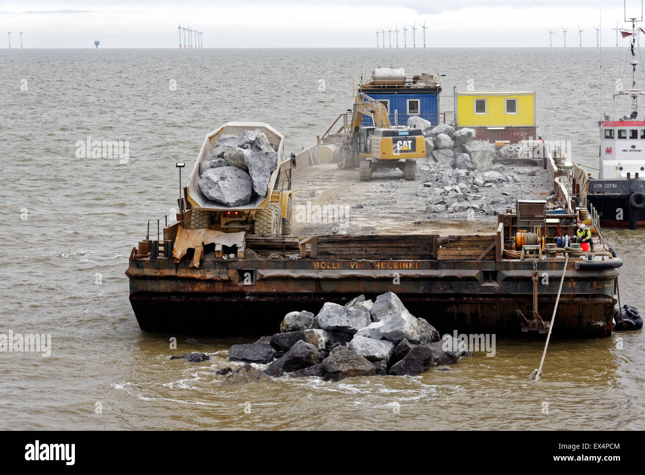 Ein Lastkahn wird verwendet, um Küstenschutzes - ein LKW dumping riesige Felsbrocken ins Meer, um einen Wellenbrecher zu machen. Clacton-on-Sea Essex Stockfoto