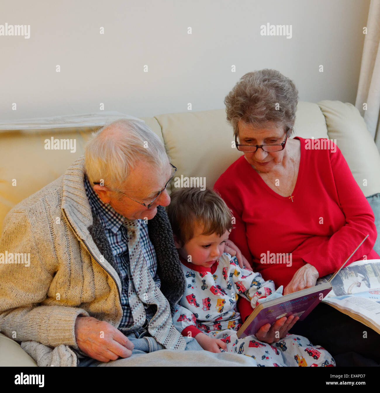 Ein Kleinkind (3 Jahre alt) im Schlafanzug mit einer Gute-Nacht-Geschichte mit seinen Großeltern Stockfoto