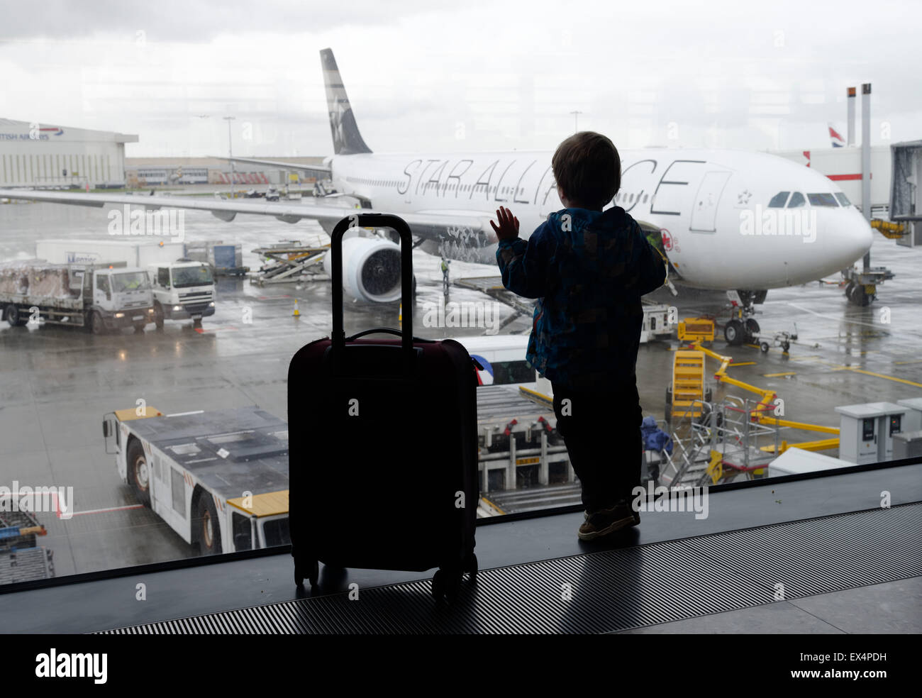 Ein kleiner Junge aus einem Flughafen Fenster betrachten die Flugzeuge Stockfoto