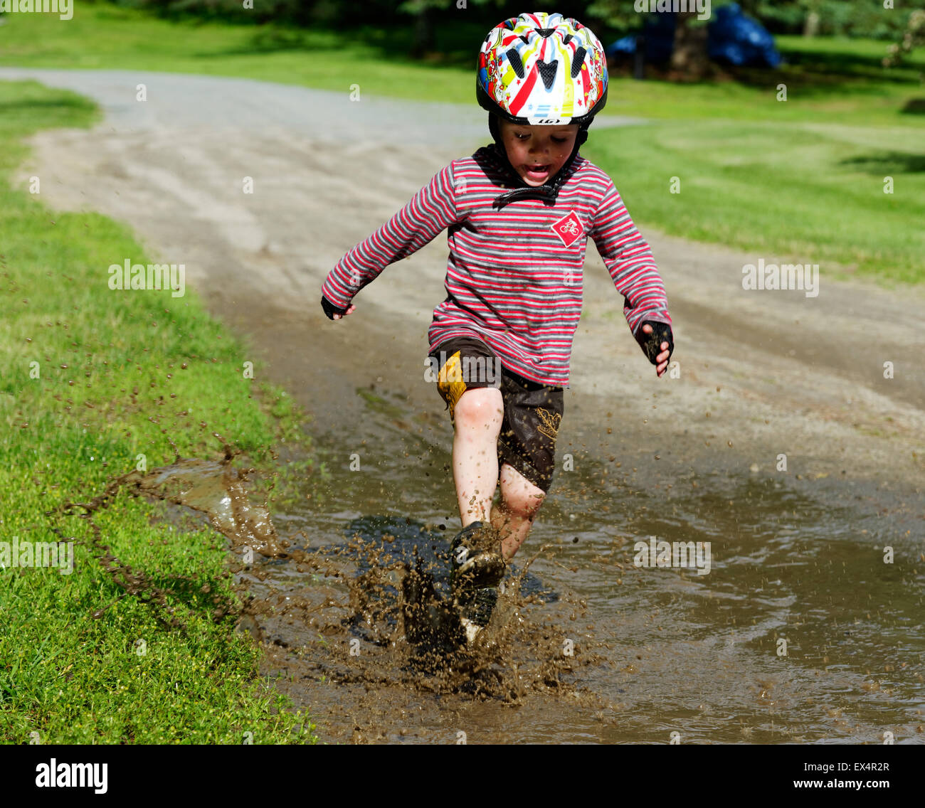 Ein Junge (3 Jahre alt) junge in einer schlammigen Pfütze springen Stockfoto