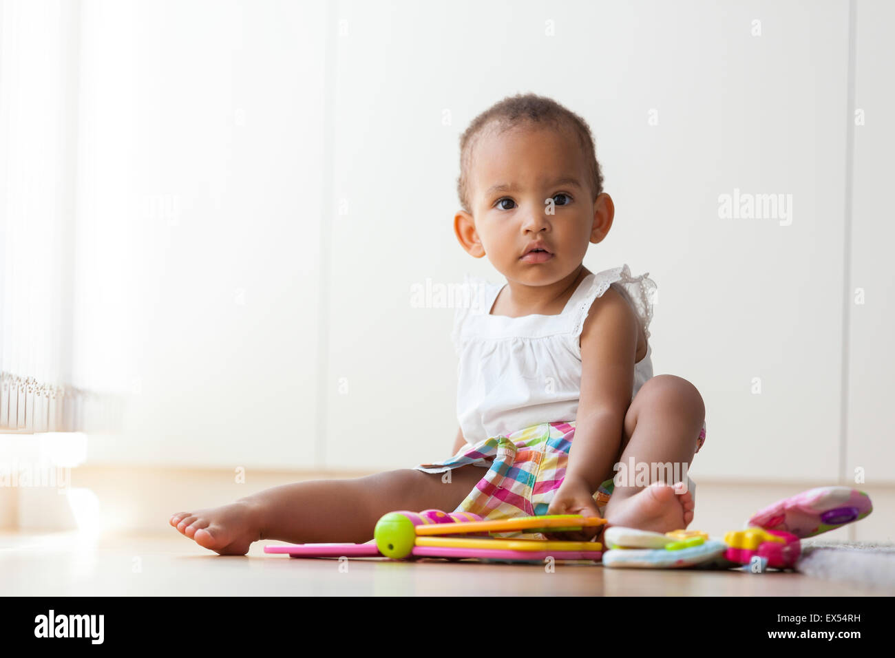 Porträt des afroamerikanischen kleine Mädchen auf dem Boden sitzen und spielen - Menschen mit schwarzer Hautfarbe Stockfoto