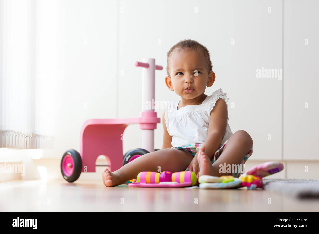 Porträt des afroamerikanischen kleine Mädchen auf dem Boden sitzen und spielen - Menschen mit schwarzer Hautfarbe Stockfoto