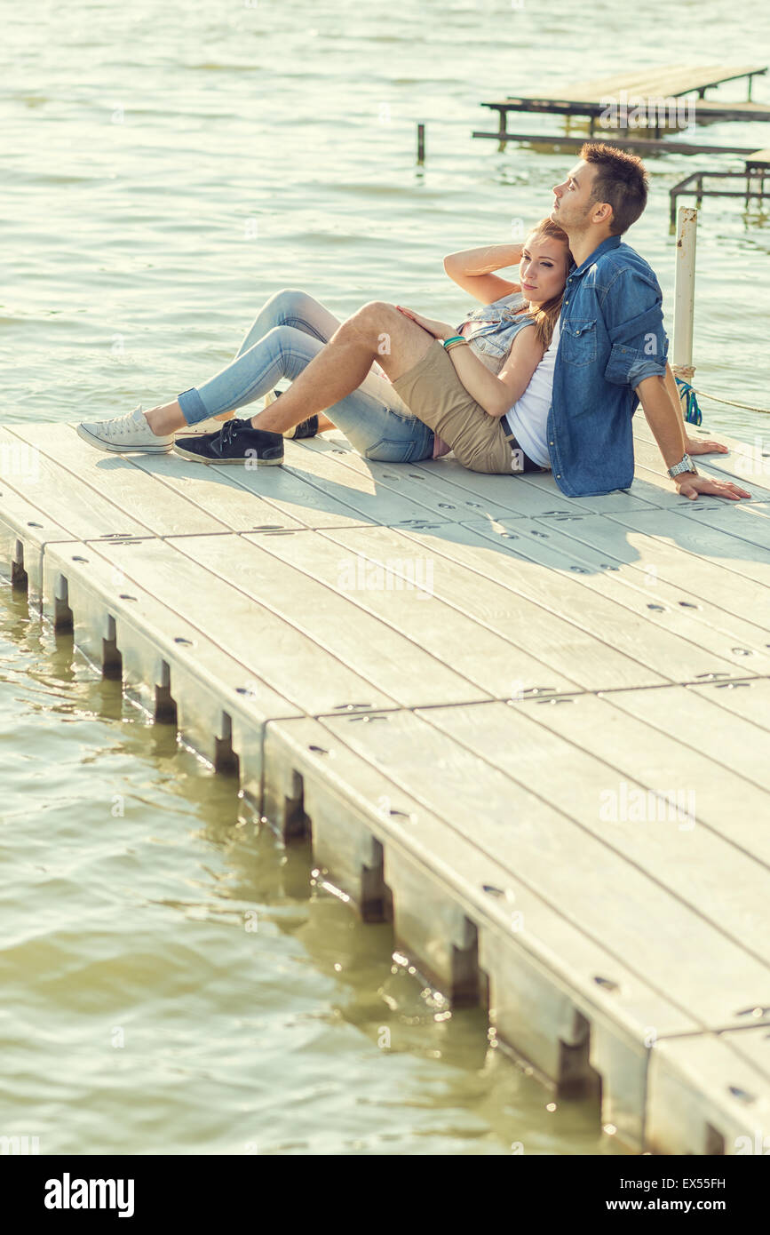 Paar in Liebe sitzen auf dem Pier, umarmen Stockfoto