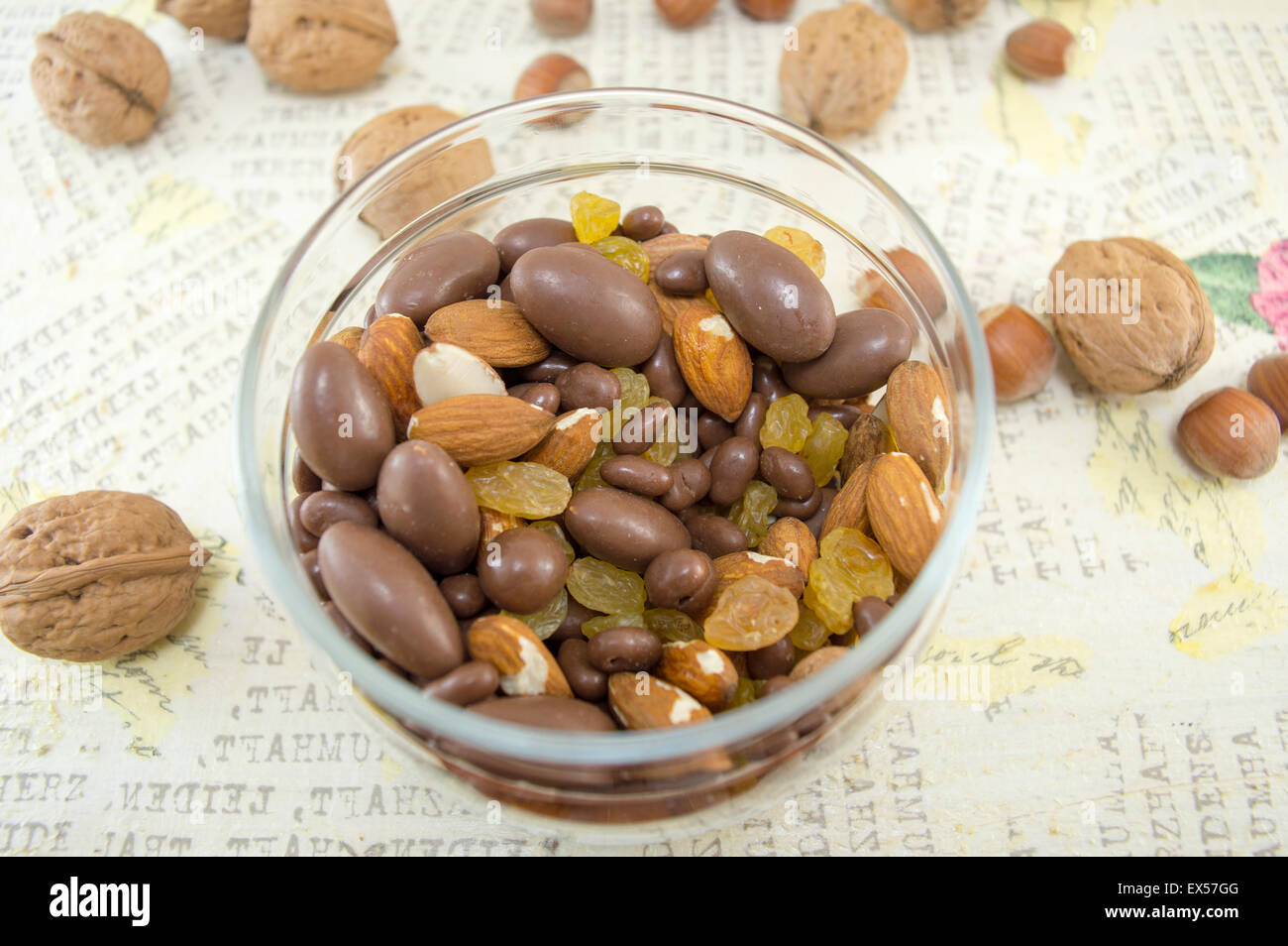 Snack-Mix aus Nüssen, Rosinen, Haselnüsse, Mandeln und Schokolade in der Schüssel auf dem Tisch Serviettentechnik dekoriert Stockfoto
