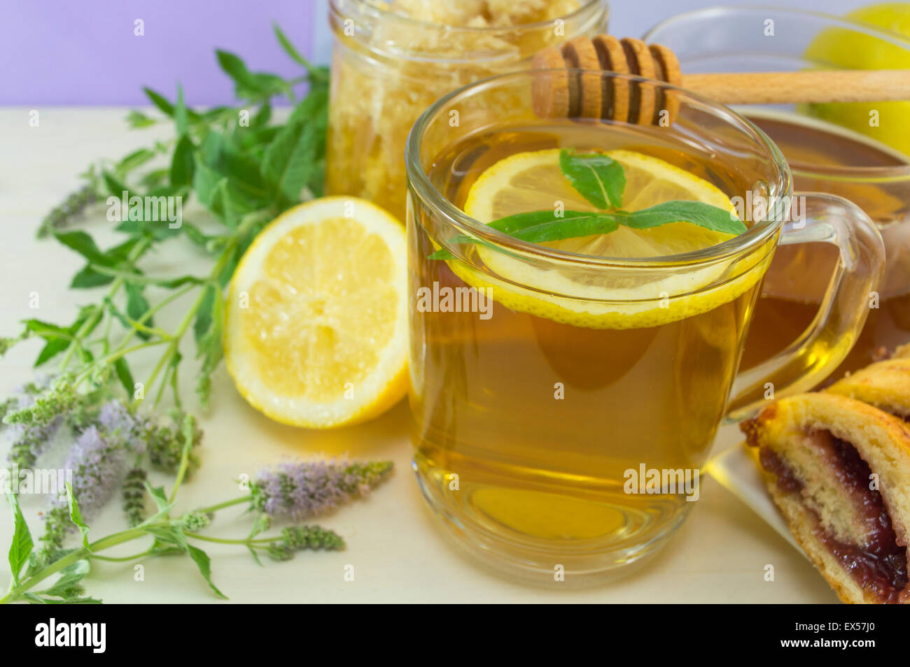Kalten gesunden Pfefferminztee mit Zitrone auf einem Tisch mit Minze Pflanze, Honig, Wasseramsel und dessert Stockfoto