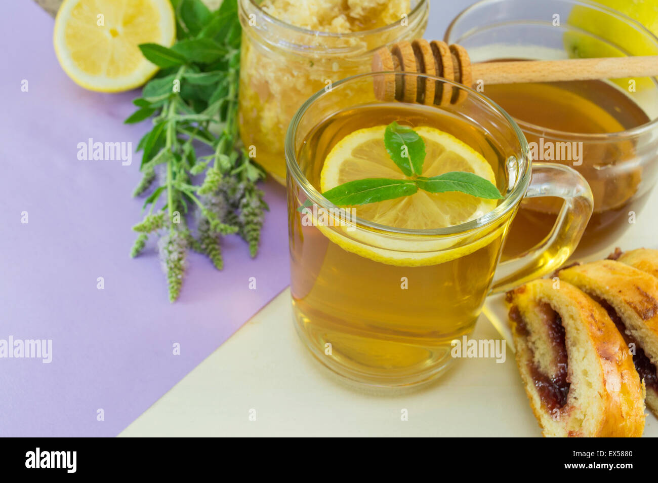 Kalten gesunden Pfefferminztee mit Zitrone auf einem Tisch mit Minze Pflanze, Honig, Wasseramsel und dessert Stockfoto