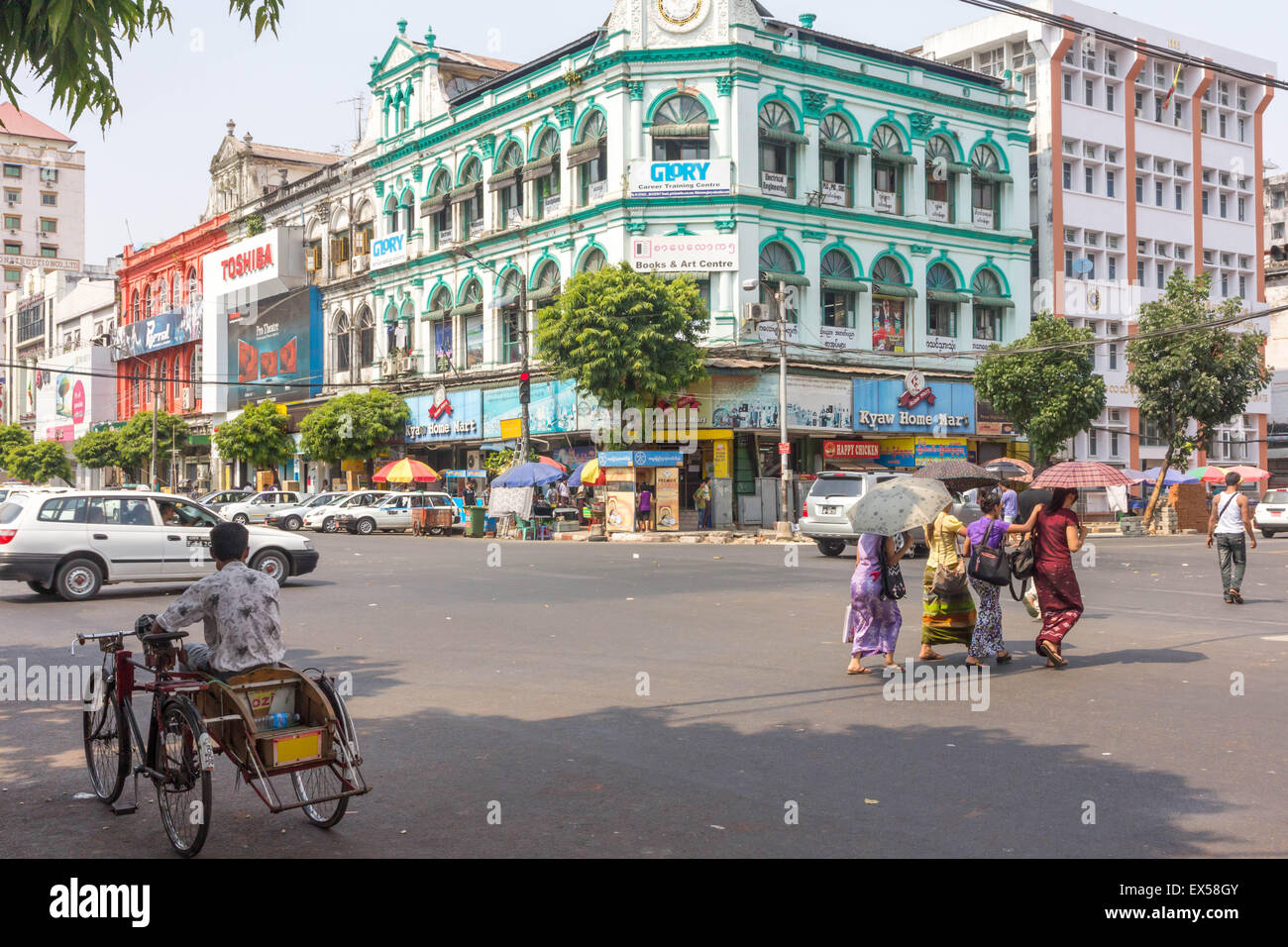 Yangon, Myanmar-Mai 4. 2014: Menschen, die die Straße überqueren. Sonnenschirme werden häufig von Menschen verwendet, um der heißen Sonne zu schützen. Stockfoto