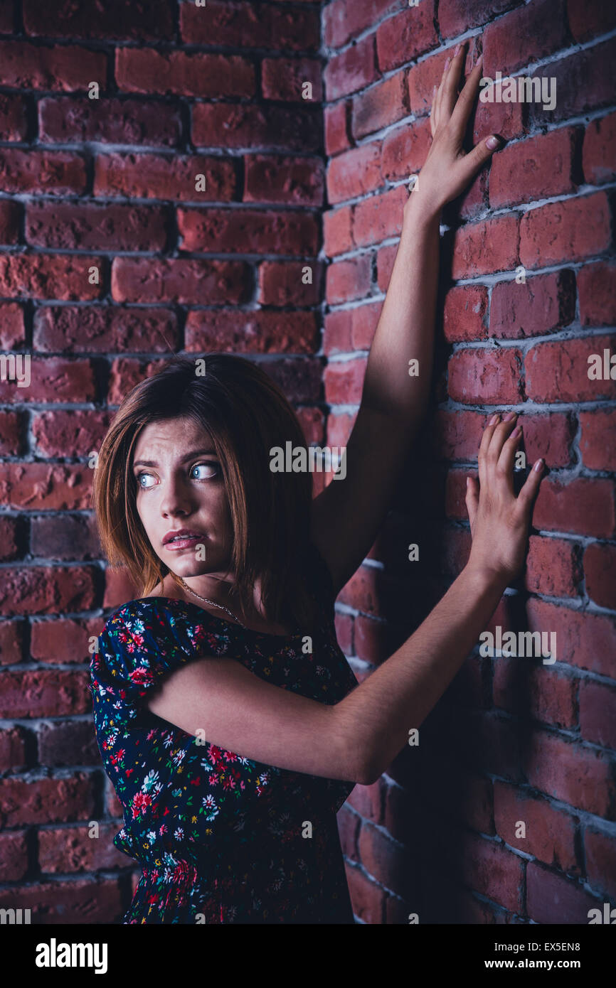 Junge Frau in die Ecke der Mauer stehen und wegsehen Angst Stockfoto