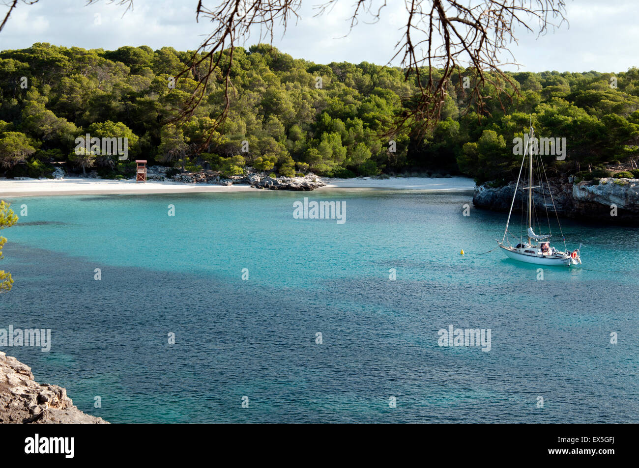 Eine Segelyacht vor Anker in den ruhigen türkisfarbenen Gewässern bei Cala Turqueta auf der Insel Menorca Spanien Stockfoto