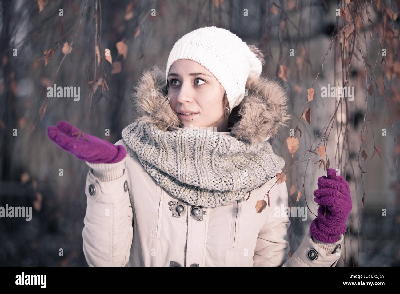 Winter-Schönheit-Mode. Freudige Gesicht Mädchen gestikulieren mit trendigen Pelzmütze für ihre Augen an einem verschneiten Tag. Emotionen. High-Fashion-Portrait-Winterlandschaft. Stockfoto