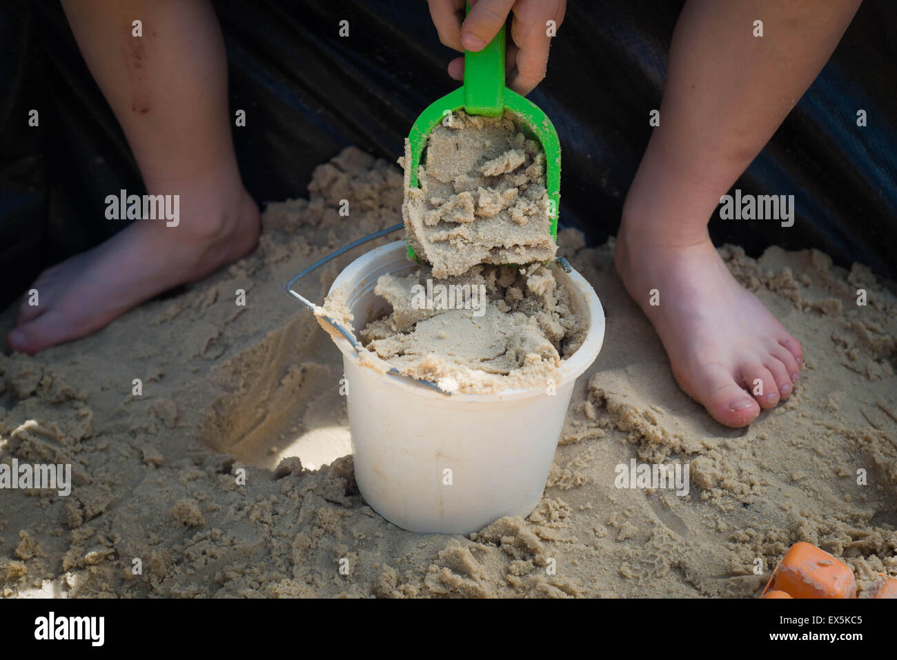 Jungen spielen im Sandkasten mit Eimer und Spaten Stockfoto