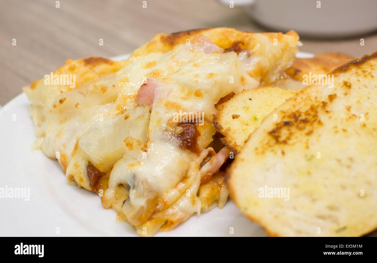 Detailansicht der eine appetitliche Schinken und Ananas italienische Pizza mit Knoblauchbrot Stockfoto