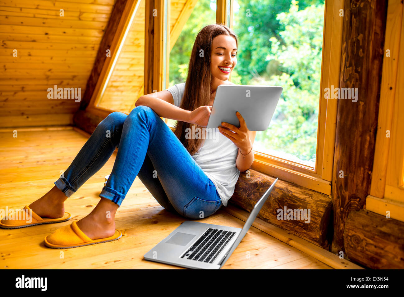 Frau mit Tablet-PC in der Nähe der Fenster im Haus Stockfoto