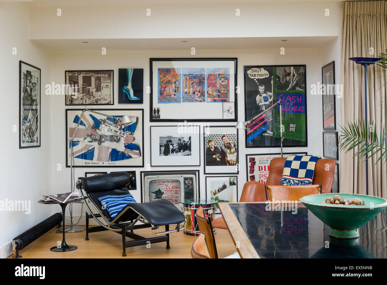 Eine Vielzahl von Clash bezogene Kunstwerk ziert eine Wand im Wohnzimmer mit Corbusier-Stil Stühle Stockfoto