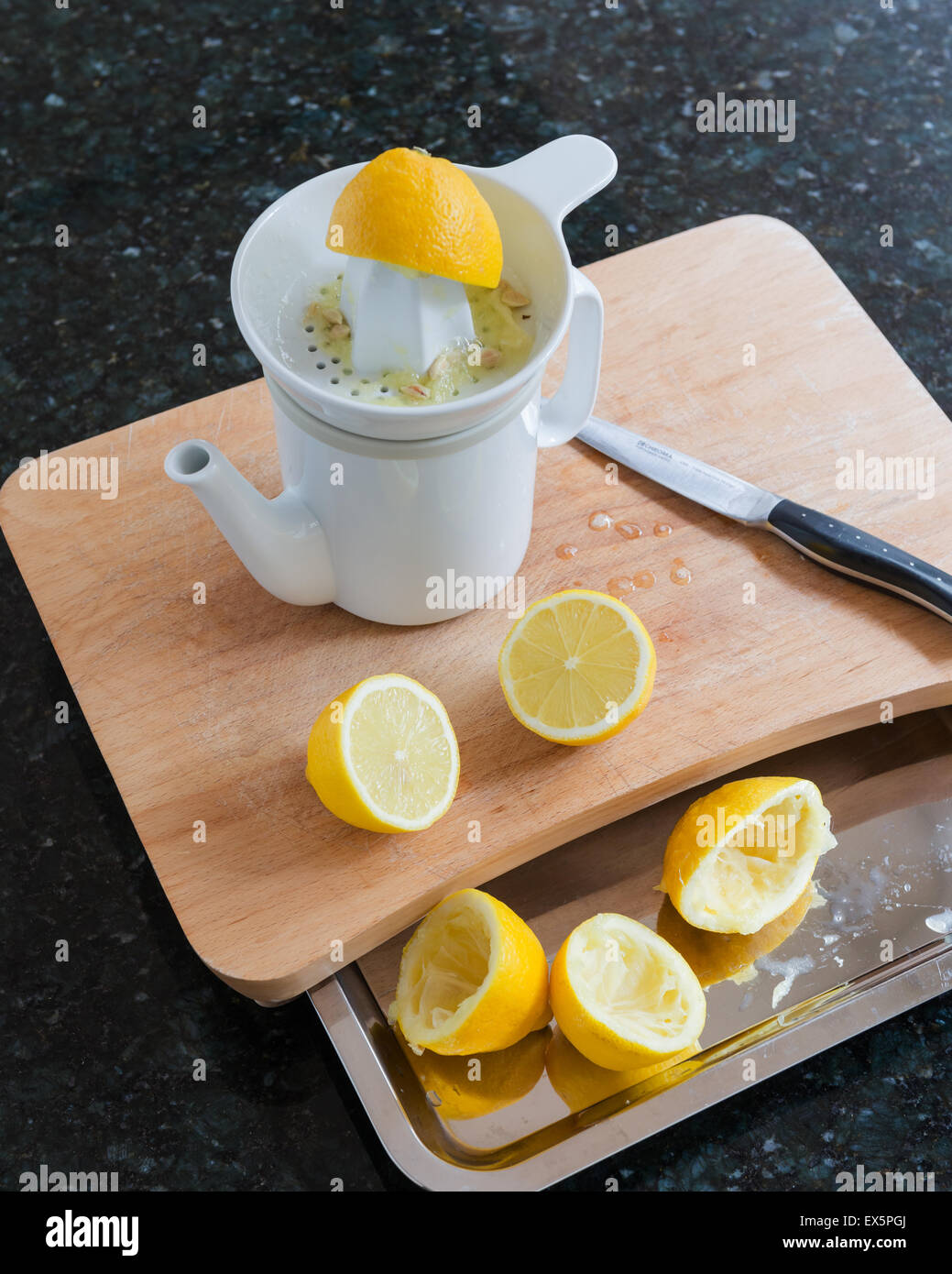 Keramische Zitronenpresse und Krug, entworfen von Conran auf hölzernen Choopping Board mit halbierten Zitronen Stockfoto