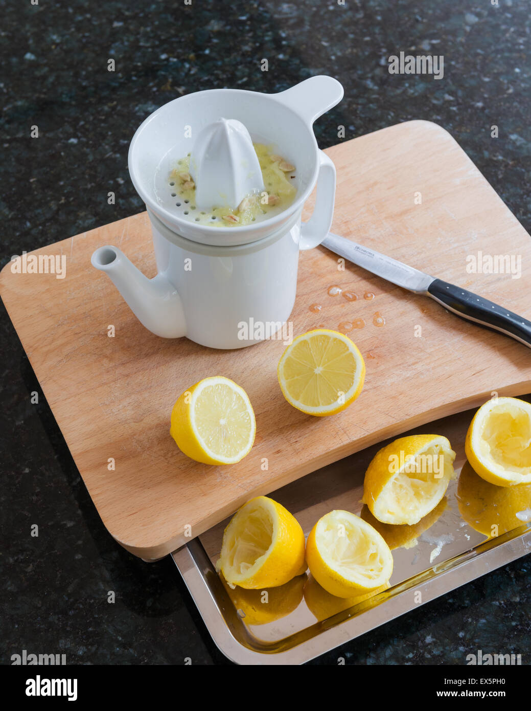 Keramische Zitronenpresse und Krug, entworfen von Conran auf hölzernen Choopping Board mit halbierten Zitronen Stockfoto