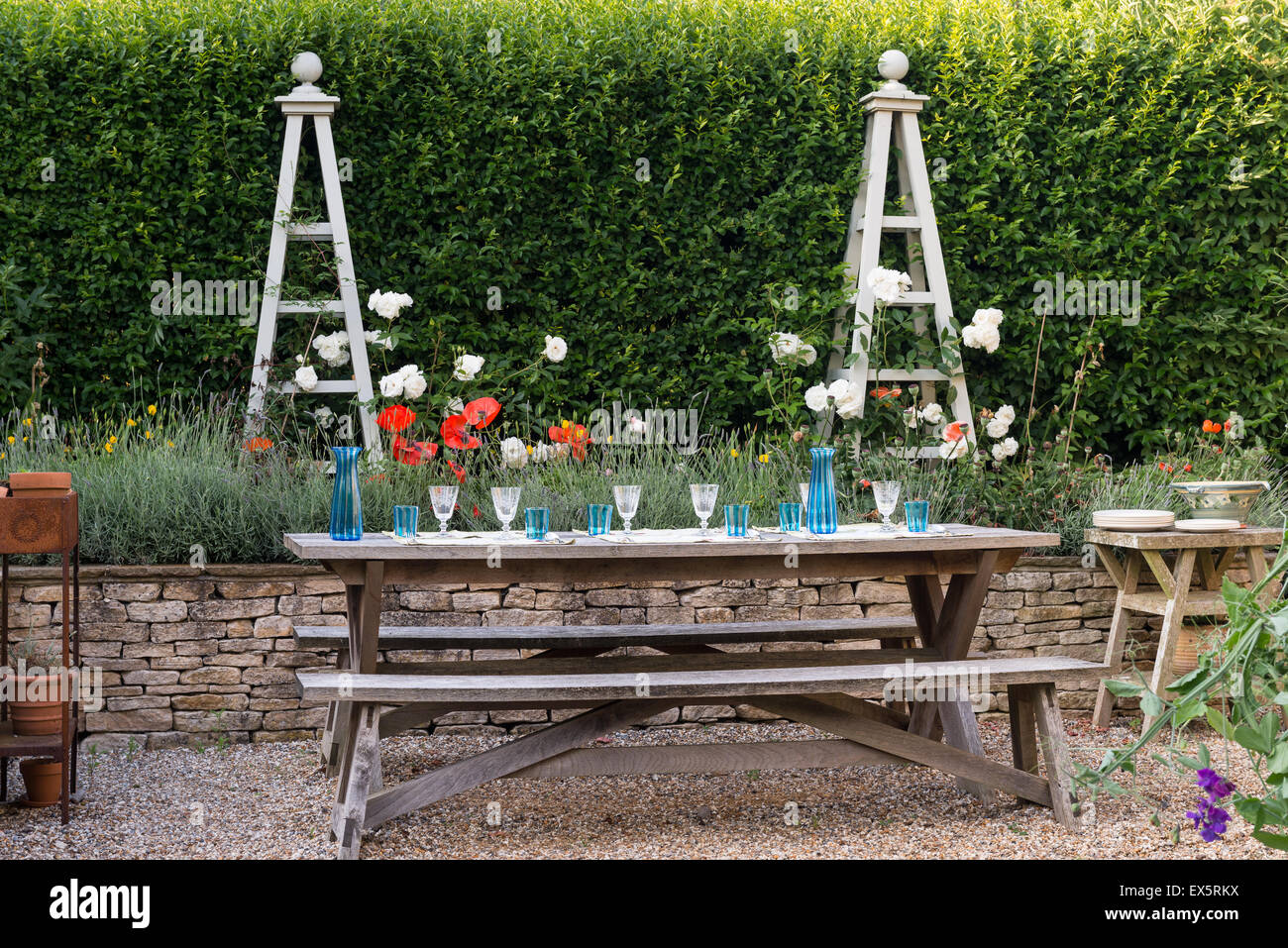 Picknickbank im Garten mit Lavendel-Bett und Pflanze steht Stockfoto