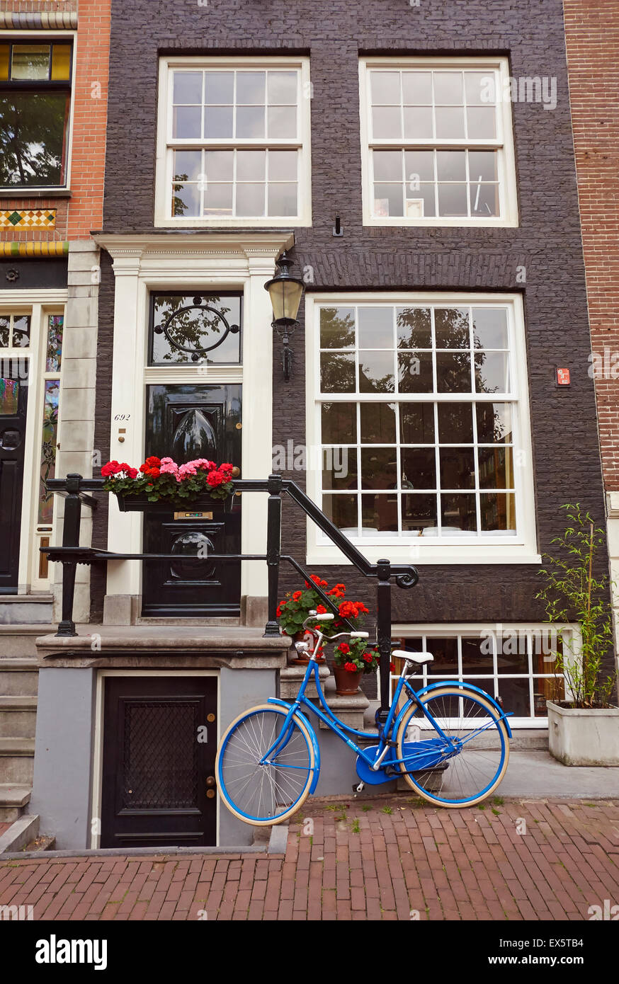 Ein blaues Fahrrad geparkt außerhalb eines typisch holländischen Hauses in Amsterdam, Niederlande, EU. Stockfoto