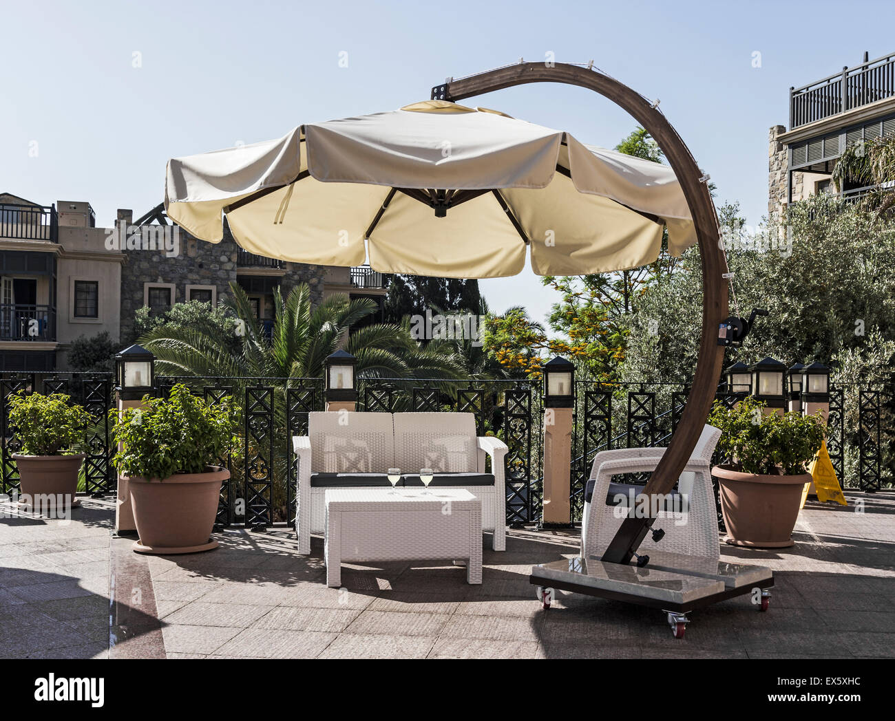 Tisch und liege im Urlaubsort mit zwei Gläsern von einem Sonnenschirm beschattet Stockfoto