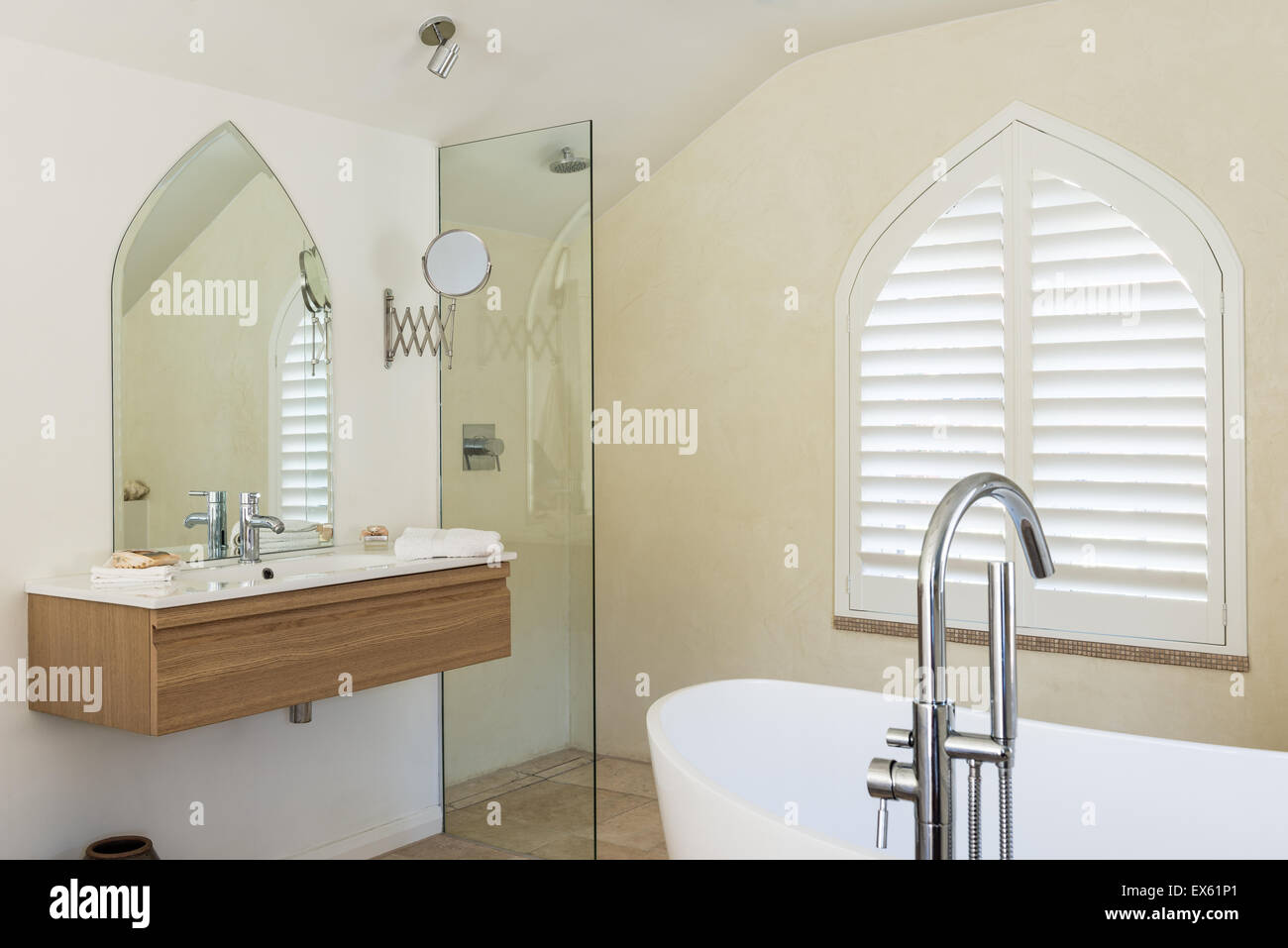 Loft-Stil-Schlafzimmer mit Balkendecke und gotisches Fenster. Das Kalkstein-Bad ist von Victoria & Albert und die Armaturen Waschbecken und sh Stockfoto