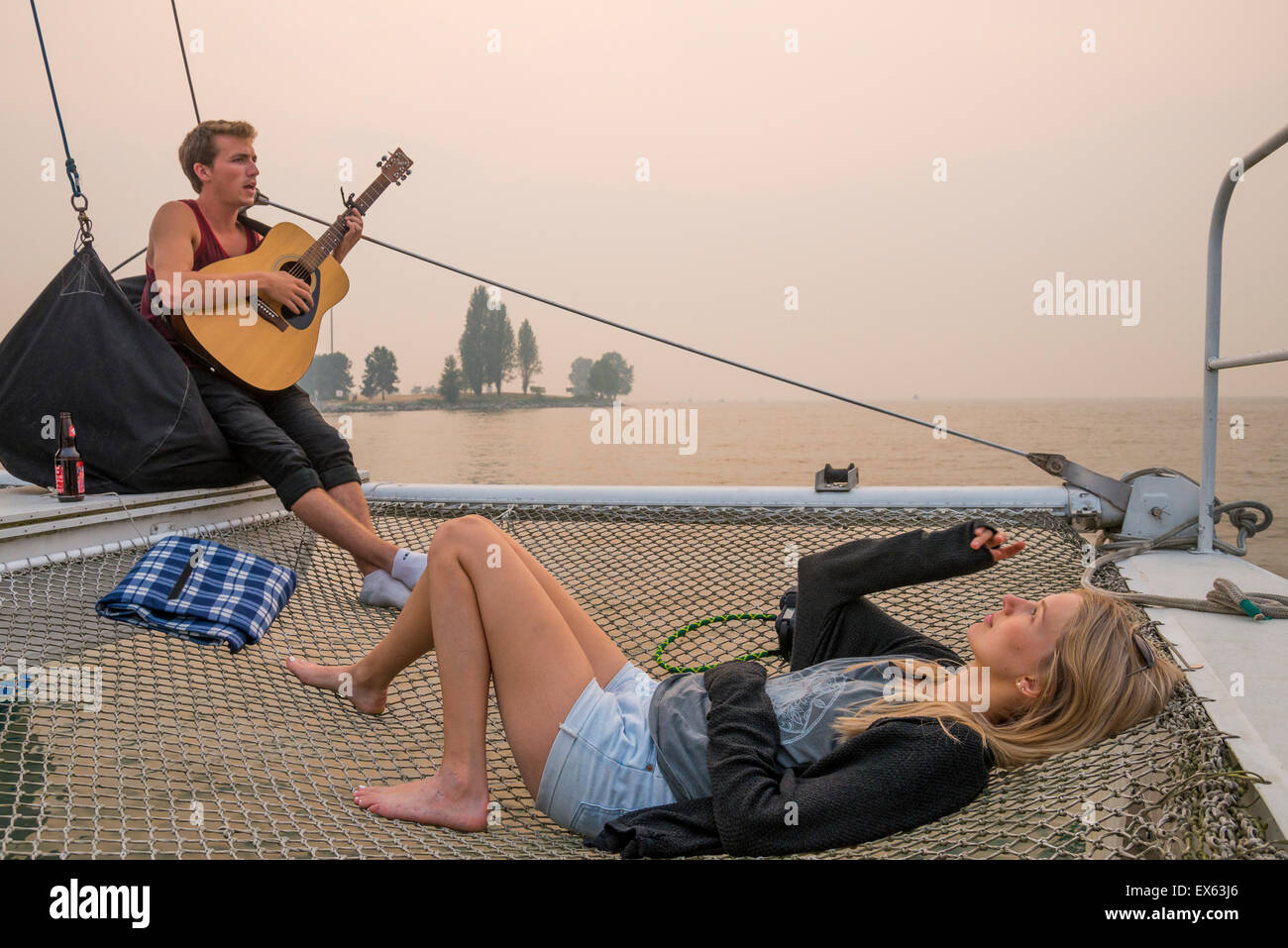 Luke Wallace spielt Gitarre an Bord Solar angetriebene Katamaran, Antenne Meer, gedockt im False Creek, Vancouver, Britisch-Kolumbien, Kanada Stockfoto