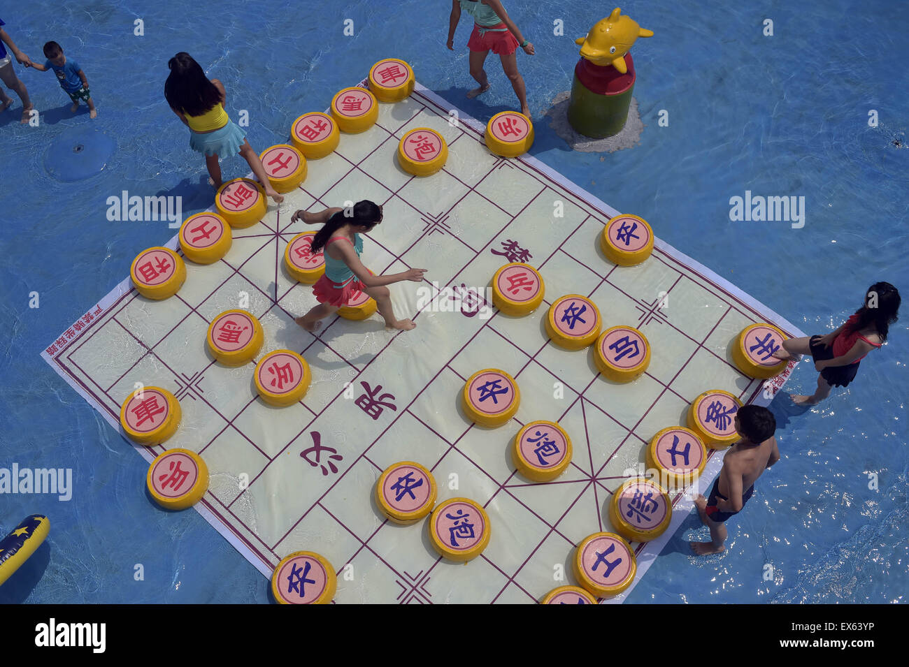 Chongqing, Chongqing, CHN. 7. Juli 2015. Chongqing, CHINA - 7. Juli 2015: (Nur zur redaktionellen Verwendung. CHINA aus) Menschen erleben Sie die Freude des Spielens chinesisches Schach im Wasser während einer Schachpartie im Wasserpark auf Yangren Straße. Wie Chongqing in heißen Tagen kommt, kurzem Wasserpark in Yangren Straße Unterhaltung des chinesischen Schach im Wasser für Touristen Urlaub verbringen. Das Jaint Schachbrett ist 20ãŽ¡und der Durchmesser jedes Schachfigur beträgt 50 cm. Credit: SIPA Asien/ZUMA Draht/Alamy Live News Stockfoto