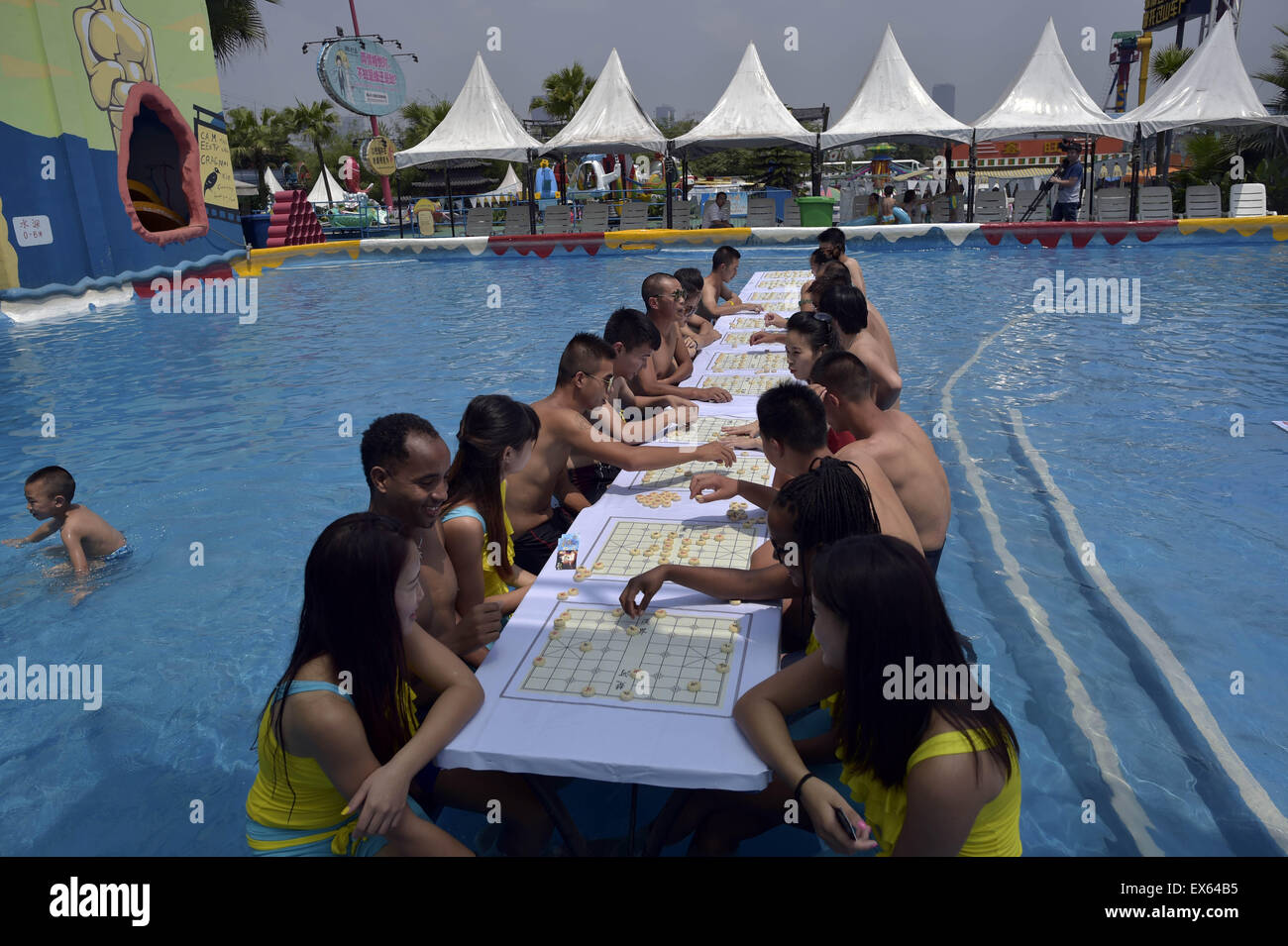Chongqing, Chongqing, CHN. 7. Juli 2015. Chongqing, CHINA - 7. Juli 2015: (Nur zur redaktionellen Verwendung. CHINA aus) Menschen erleben Sie die Freude des Spielens chinesisches Schach im Wasser während einer Schachpartie im Wasserpark auf Yangren Straße. Wie Chongqing in heißen Tagen kommt, kurzem Wasserpark in Yangren Straße Unterhaltung des chinesischen Schach im Wasser für Touristen Urlaub verbringen. Das Jaint Schachbrett ist 20ãŽ¡und der Durchmesser jedes Schachfigur beträgt 50 cm. Credit: SIPA Asien/ZUMA Draht/Alamy Live News Stockfoto