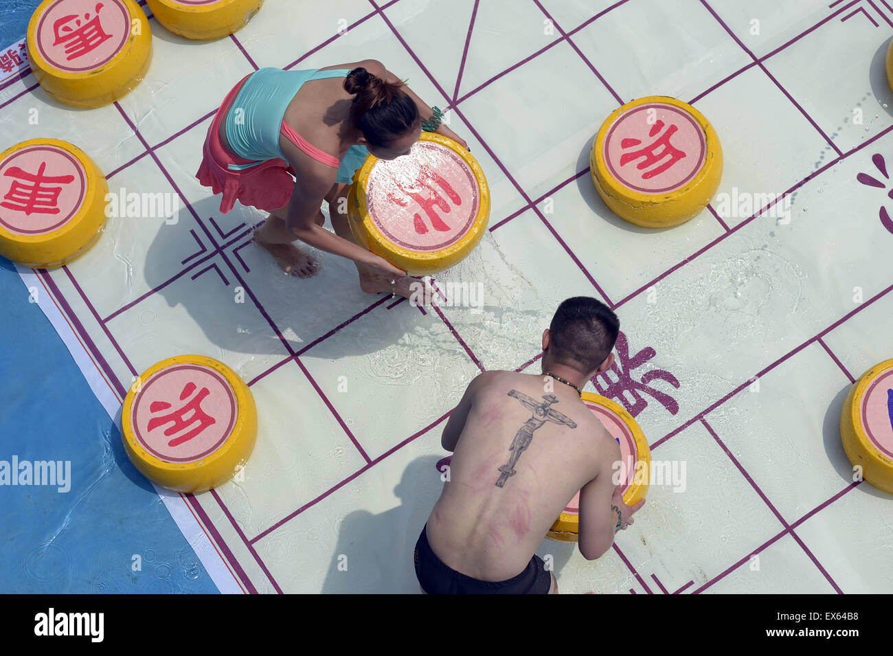 Chongqing, Chongqing, CHN. 7. Juli 2015. Chongqing, CHINA - 7. Juli 2015: (Nur zur redaktionellen Verwendung. CHINA aus) Menschen erleben Sie die Freude des Spielens chinesisches Schach im Wasser während einer Schachpartie im Wasserpark auf Yangren Straße. Wie Chongqing in heißen Tagen kommt, kurzem Wasserpark in Yangren Straße Unterhaltung des chinesischen Schach im Wasser für Touristen Urlaub verbringen. Das Jaint Schachbrett ist 20ãŽ¡und der Durchmesser jedes Schachfigur beträgt 50 cm. Credit: SIPA Asien/ZUMA Draht/Alamy Live News Stockfoto