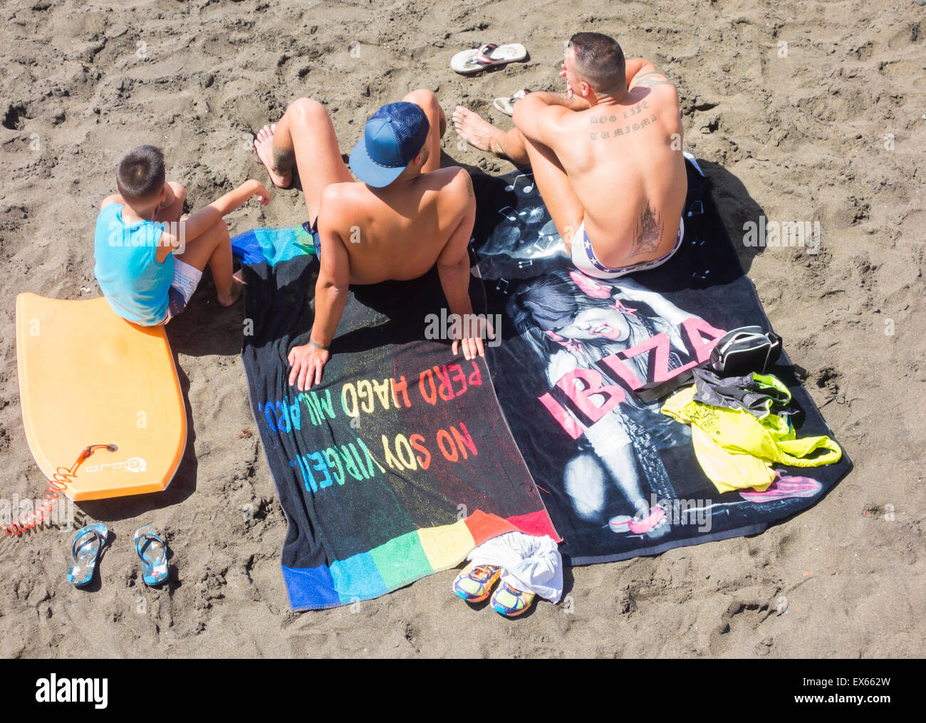 Zwei Männer und jungen am Strand, einem auf Ibiza Handtuch sitzen. Stockfoto